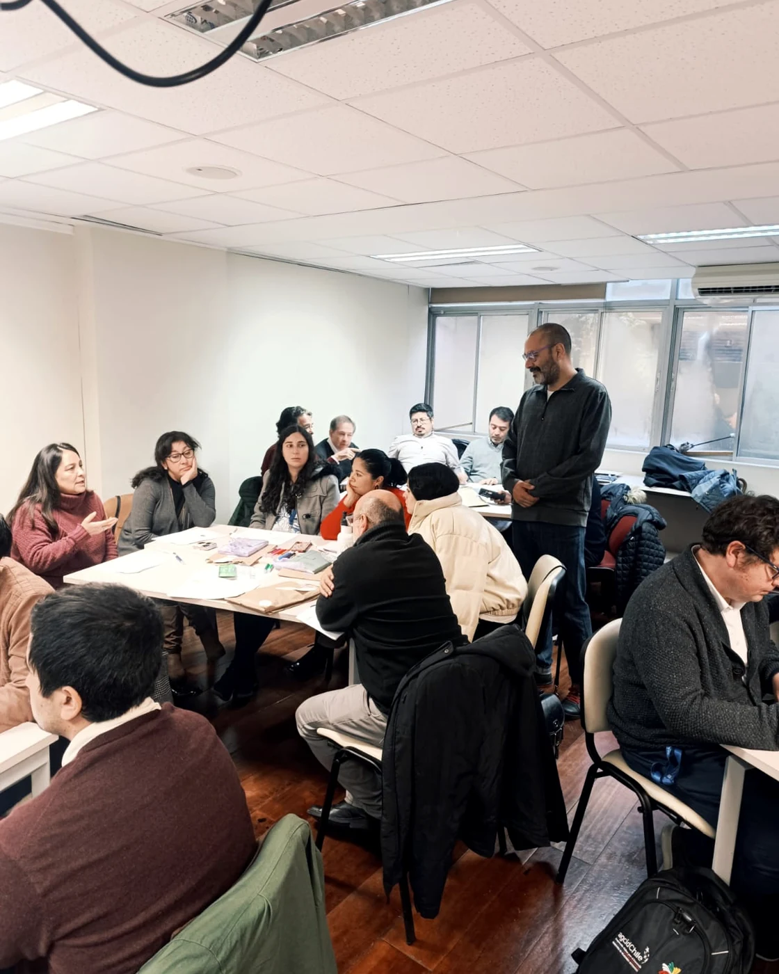 Claudio Reyes facilitando una conversación grupal y trabajo colaborativo en sala